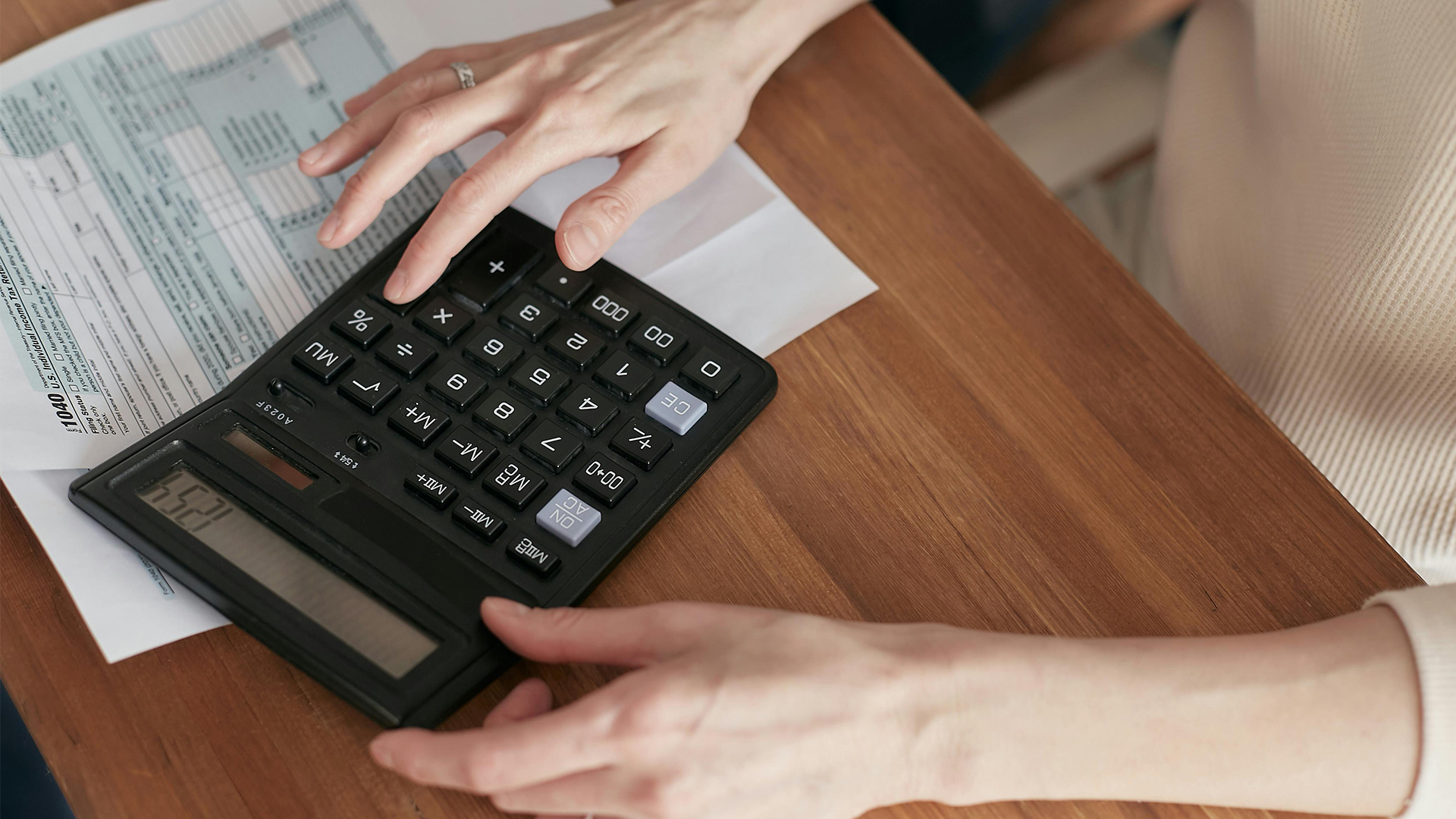 Close up of someone using a calculator sat at a desk.