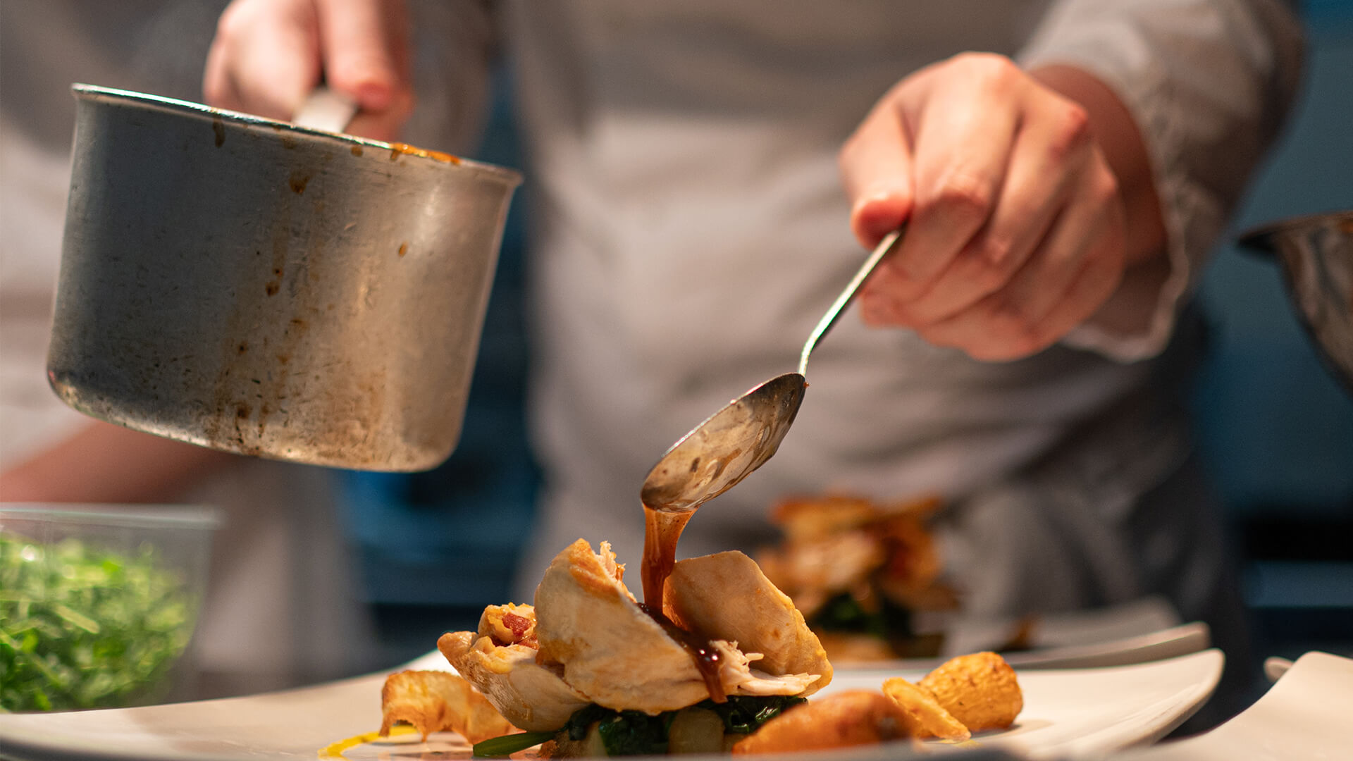Three young chefs in chef uniforms working in a kitchen.