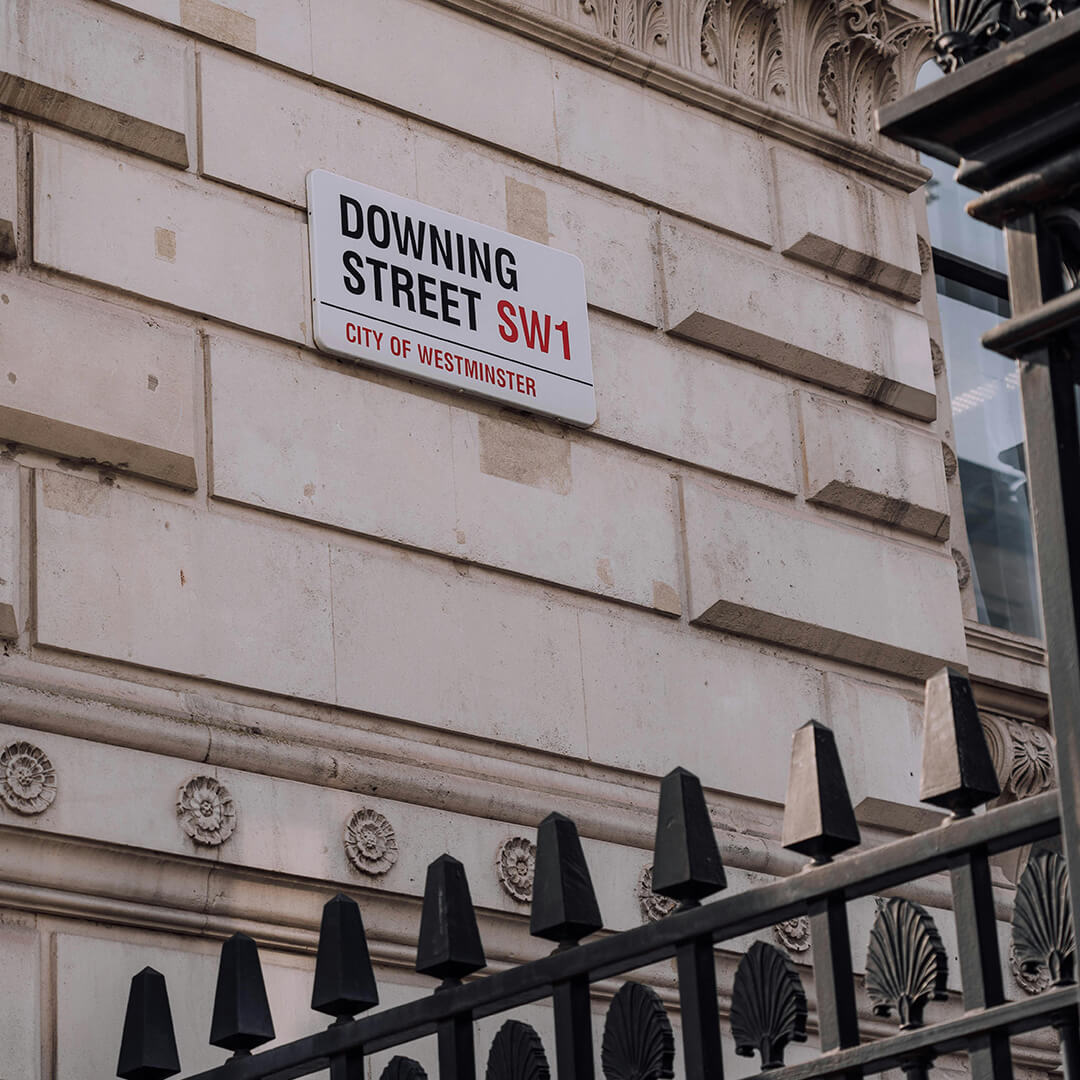 Downing Streets street sign on the wall of a building.