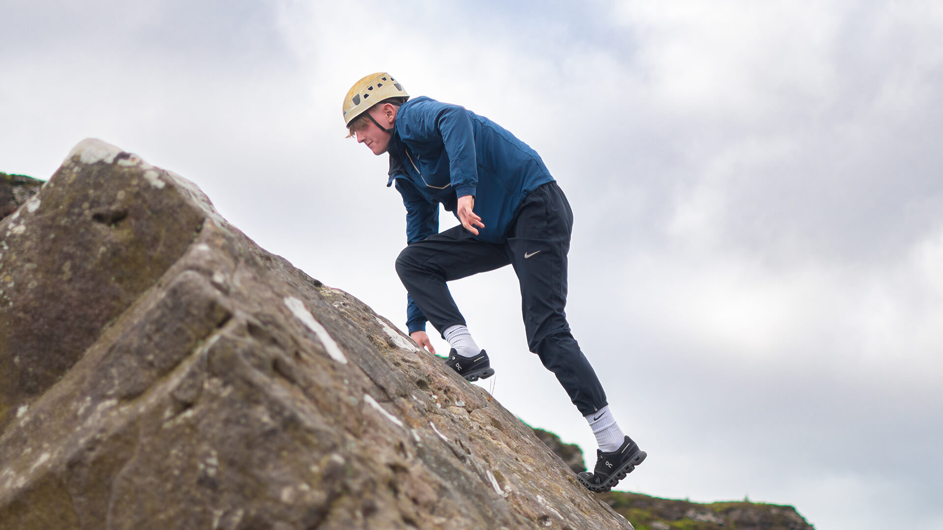 Teenager climbing up rockface